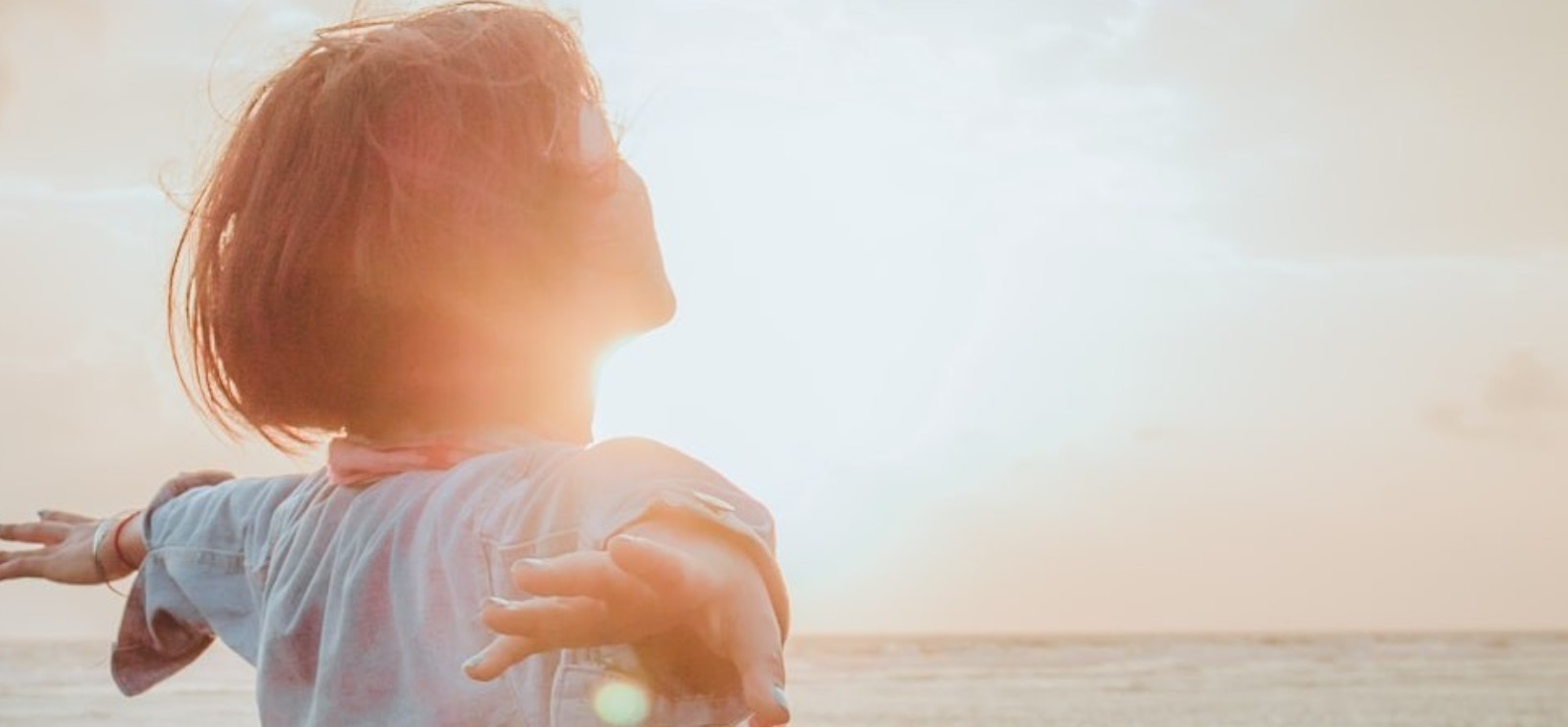 Woman enjoying a sunlit seaside moment during her menopause wellness journey
